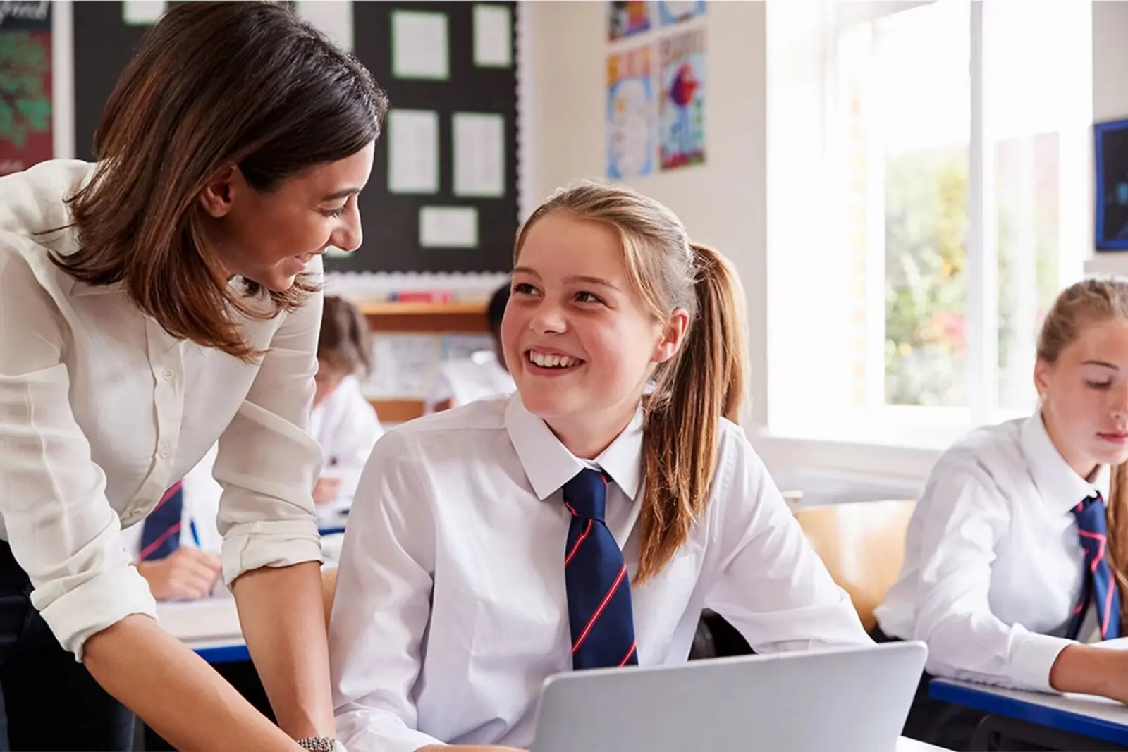 Teacher helping a student using a laptop