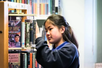 Student taking a library book off a shelf
